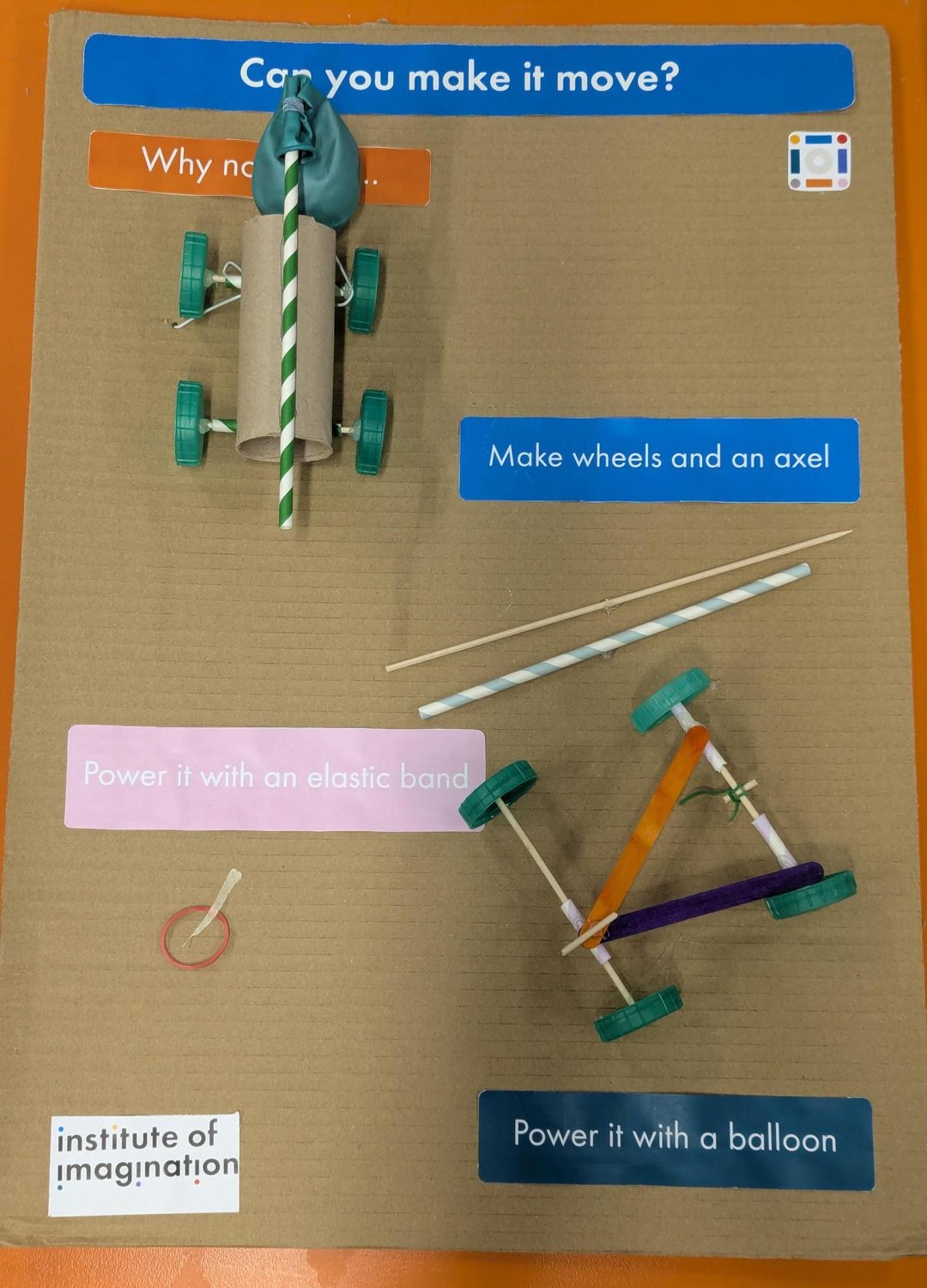 The Can you make it move? board: a balloon-powered car built from a cardboard tube on bottle-cap wheels, a labelled skewer and straw for the axle, and an elastic band car built from lolly sticks.
