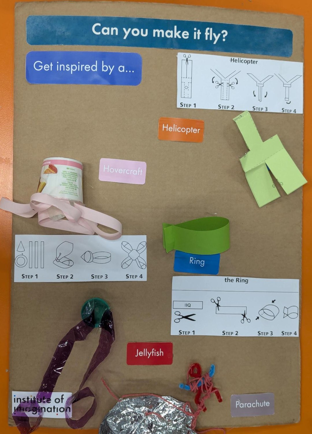 The Can you make it fly? board: the five makes labelled Helicopter, Hovercraft, Ring, Jellyfish and Parachute, each with the built object pinned beside its label, and three printed four-panel step strips.